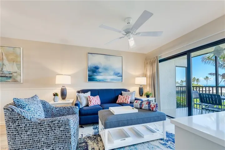 Living area featuring a ceiling fan, light-toned walls, and wainscoting