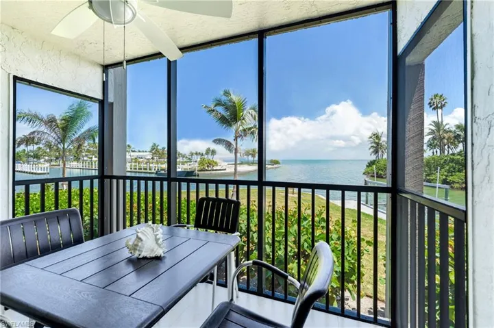 Screened balcony featuring expansive water views, a ceiling fan, and black railing