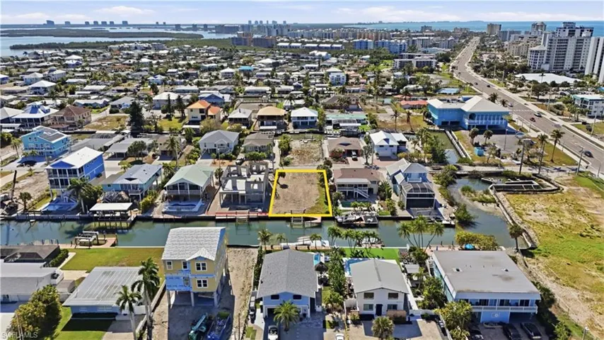 Aerial view of property and surrounding area with a nearby body of water and property boundaries highlighted - Virtually Edited Image