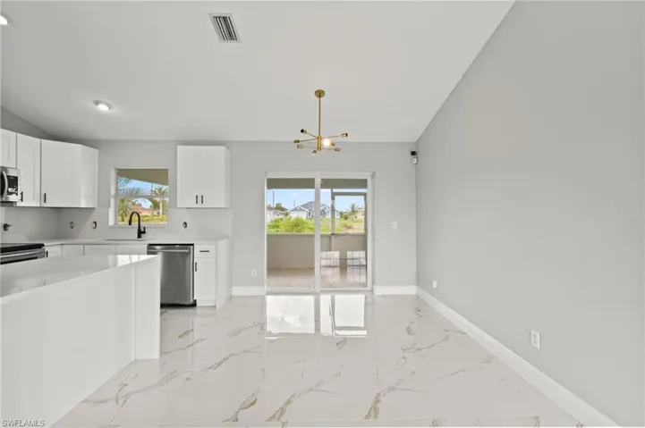 Kitchen with appliances with stainless steel finishes, white cabinetry, a chandelier, and plenty of natural light