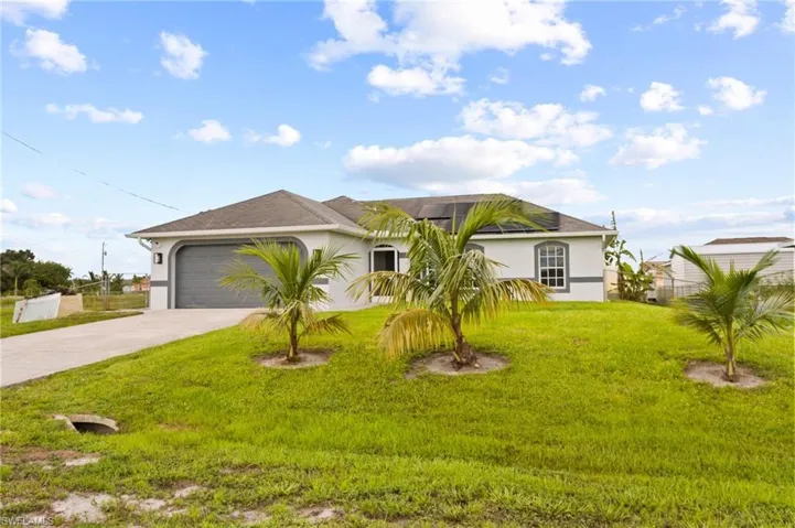 Ranch-style house featuring a garage and a front lawn