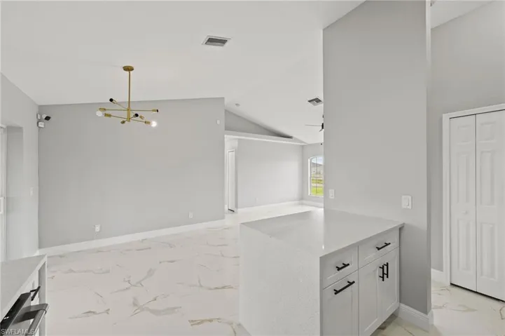 Kitchen featuring white cabinets, lofted ceiling, a chandelier, and decorative light fixtures