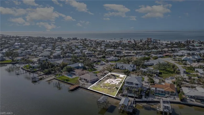 Aerial view of residential area featuring property parcel outlined and a nearby body of water