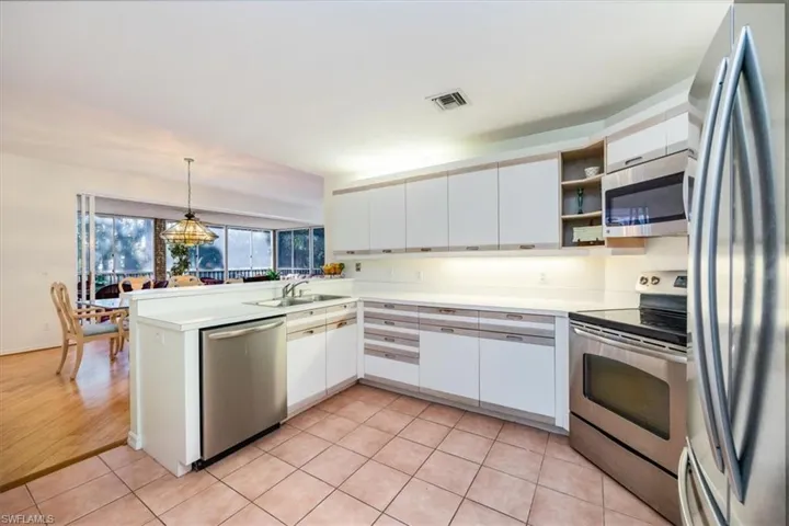 Kitchen featuring sink, hanging light fixtures, stainless steel appliances, kitchen peninsula, and white cabinets