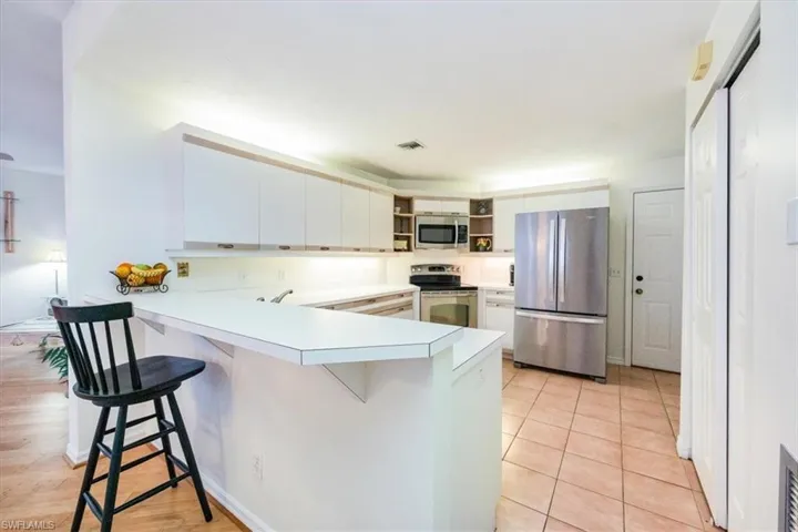 Kitchen with kitchen peninsula, white cabinetry, a breakfast bar, and stainless steel appliances
