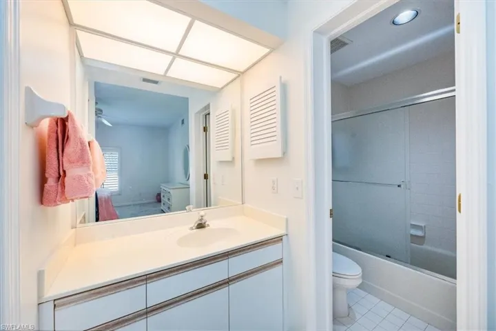 Full bathroom with toilet, tile patterned flooring, vanity, and combined bath / shower with glass door