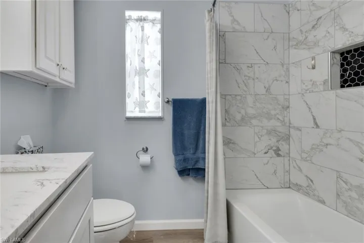 Bathroom featuring shower / tub combo with curtain, vanity, and light wood-style floors