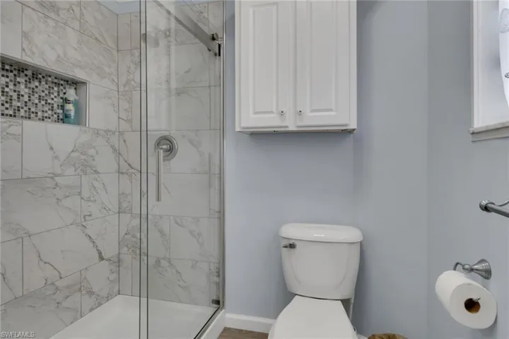 Full bath featuring a shower stall and toilet