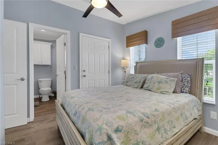 Bedroom featuring dark wood finished floors, a ceiling fan, and ensuite bath