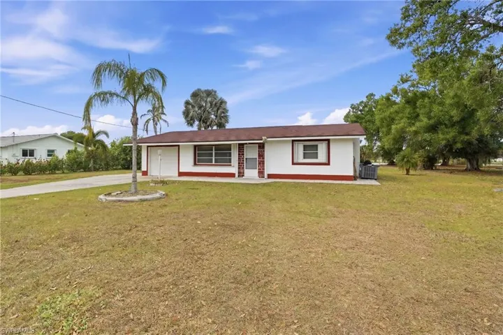 Ranch-style house featuring a front lawn, an attached garage, and concrete driveway