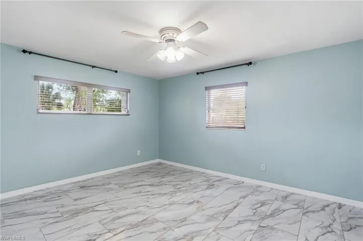 Empty room featuring light marble finish flooring and ceiling fan