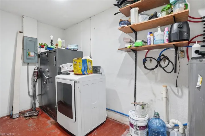 Laundry room with washer / dryer, electric panel, unfinished concrete flooring, and water heater