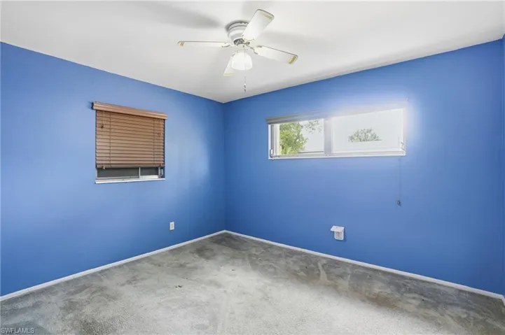 Carpeted empty room featuring ceiling fan and baseboards