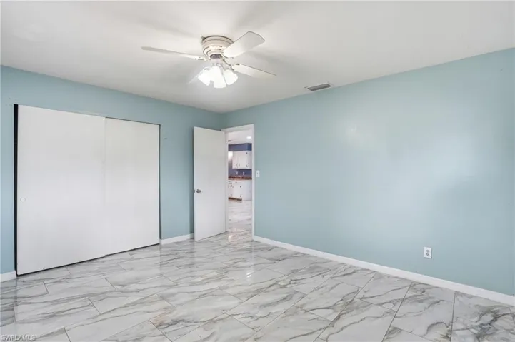 Unfurnished bedroom with light marble finish flooring, ceiling fan, and a closet