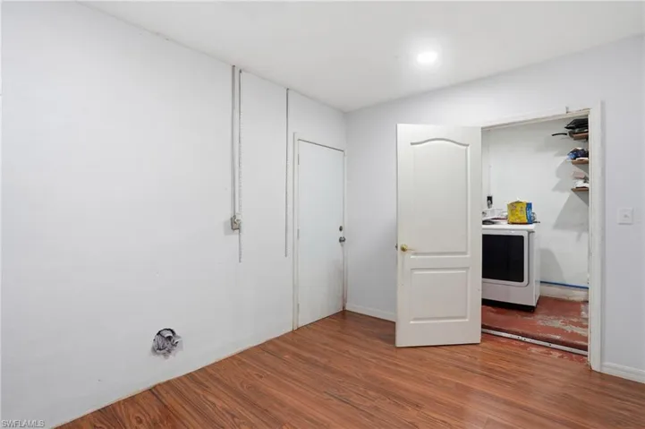 Unfurnished bedroom featuring washer / dryer and dark wood-type flooring