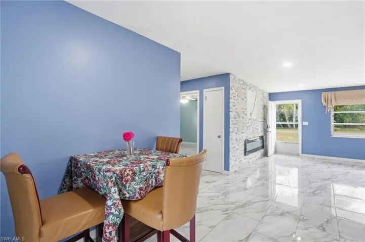 Dining room with light marble finish floors, an accent wall, and recessed lighting