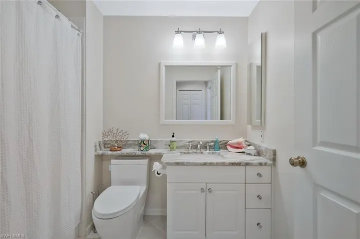 Full bath featuring vanity, a shower with shower curtain, and light tile patterned floors