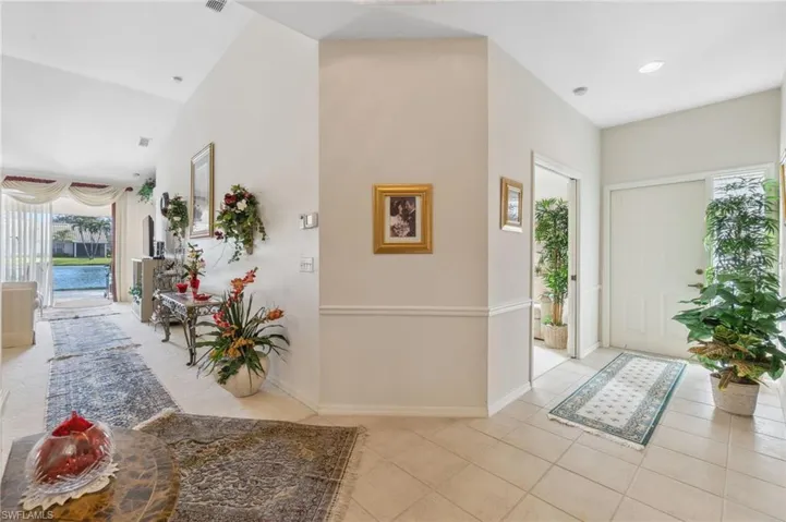 Entryway with light tile patterned flooring and lofted ceiling