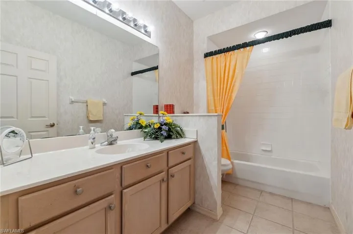 Full bathroom with vanity, shower / tub combo, toilet, and tile patterned floors