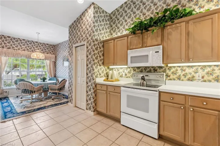 Kitchen featuring hanging light fixtures, a notable chandelier, white appliances, and light tile patterned floors