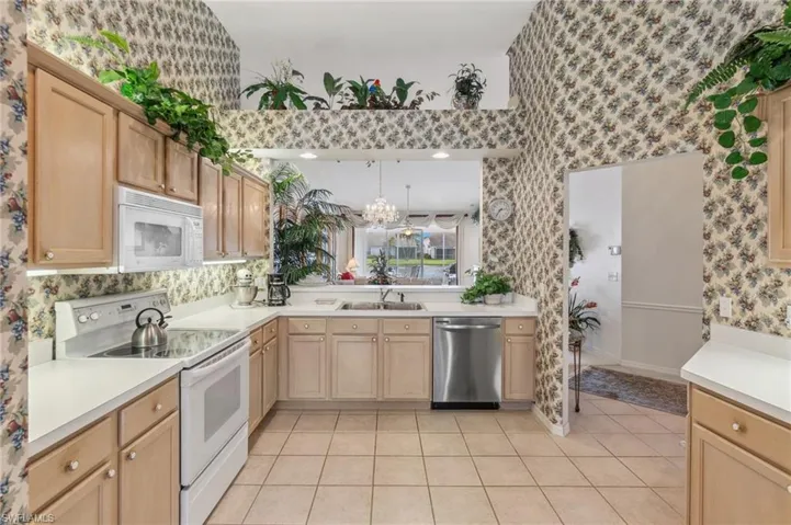 Kitchen featuring white appliances, sink, a notable chandelier, light brown cabinetry, and light tile patterned floors