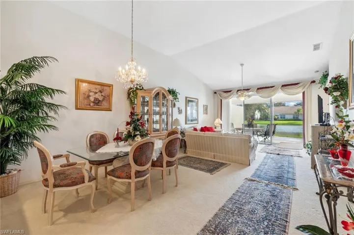 Carpeted dining room with a notable chandelier and vaulted ceiling