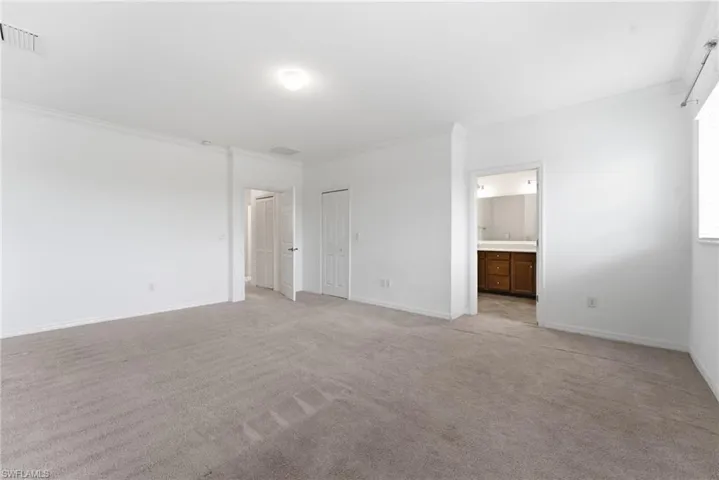 Unfurnished bedroom with crown molding, light carpet, and ensuite bath