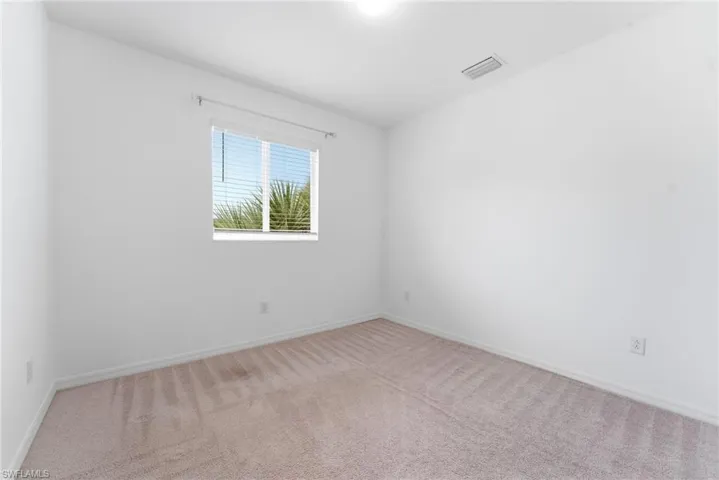 Empty room featuring light colored carpet and baseboards