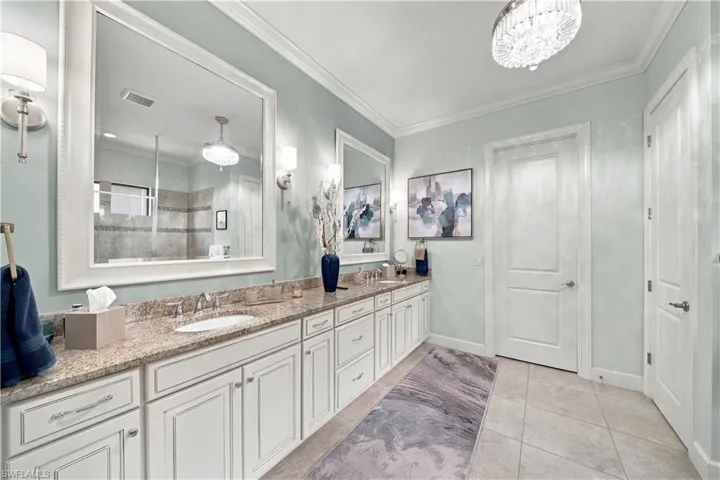 Spacious bathroom featuring a dual vanity with light-toned granite-style countertops, white cabinetry, and undermount sinks