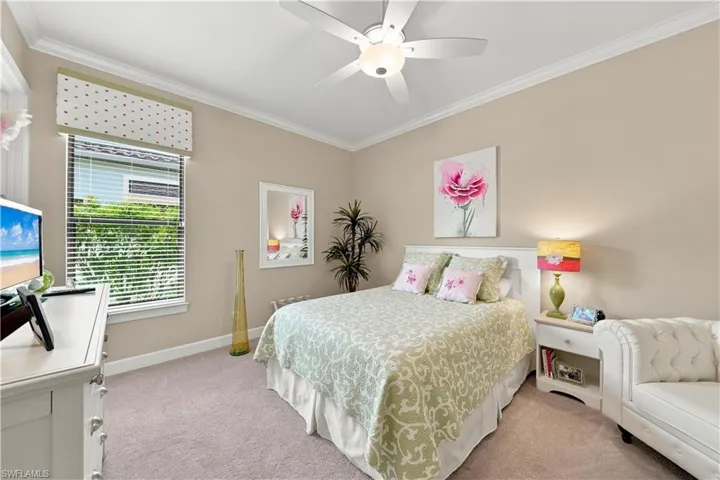 Carpeted room featuring a ceiling fan with integrated lighting, crown molding, and a window with horizontal blinds and a decorative valance