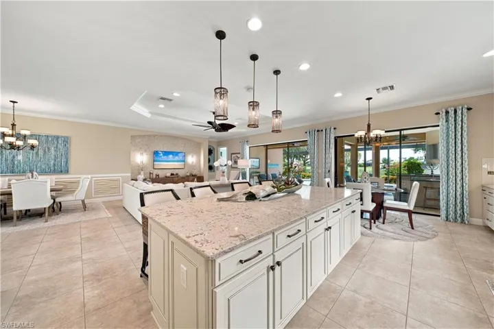 Spacious open-concept interior featuring a large kitchen island with a light-colored countertop, recessed lighting, and tile flooring