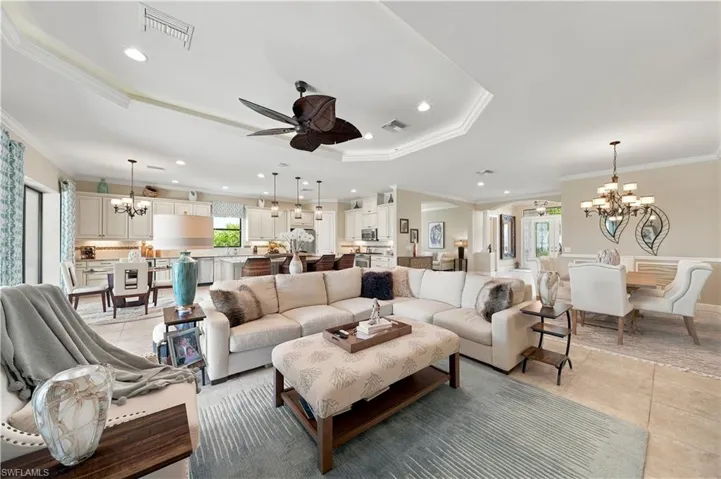 Expansive open-concept living area featuring a tray ceiling with a ceiling fan, recessed lighting, and tile flooring