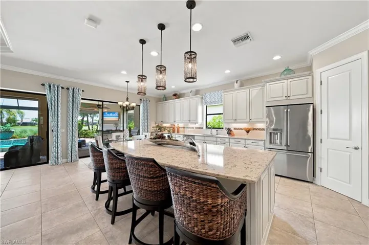 Spacious kitchen featuring a large island with a light-toned countertop, white cabinetry, stainless steel appliances, and tile flooring