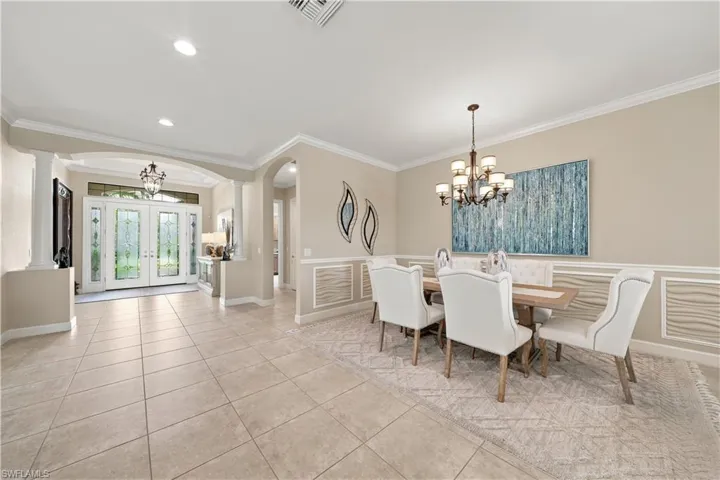 Formal dining area featuring wainscoting and crown molding, tile flooring, and a chandelier