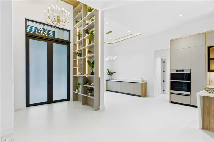 STRIKING ENTRYWAY w/ golden CHANDELIER & built-in FEATURE WALL CABINETRY w/ integrated LED ACCENT LIGHTING!
