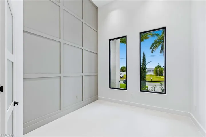 Private office/den with soaring ceilings, a stunning floor-to-ceiling paneled feature wall, and double doors for a refined work-from-home or flex space