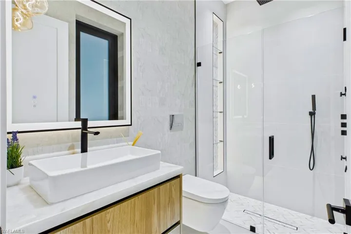 Stylish full pool bath with a glass-enclosed shower, modern vanity with vessel sink, and sleek designer finishes for easy indoor-outdoor living