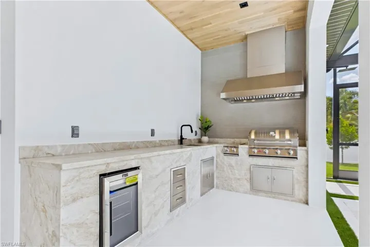 L-SHAPED OUTDOOR KITCHEN w/ Bull grill, side burner, COMMERCIAL hood, fridge, sink & storage &