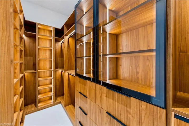 Oversized dual walk-in custom closets w/ illuminated display cabinetry & dedicated purse/display shelving
