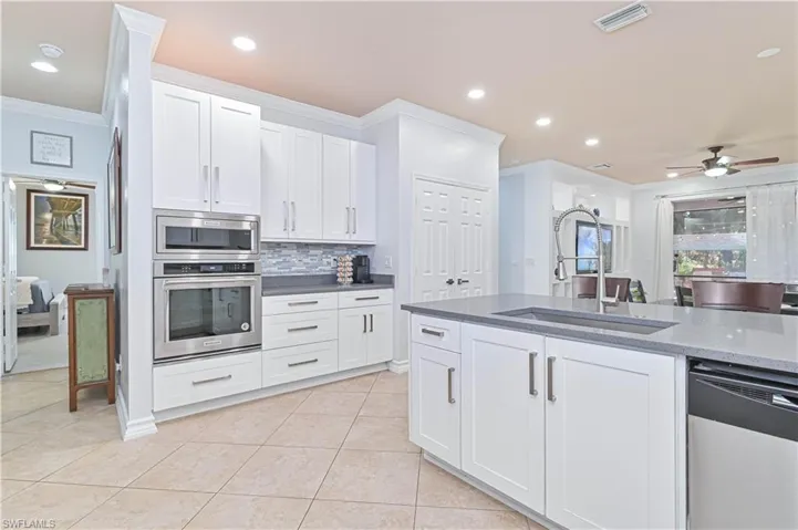 Kitchen with white cabinetry, a ceiling fan, stainless steel appliances, dark stone counters, and ornamental molding