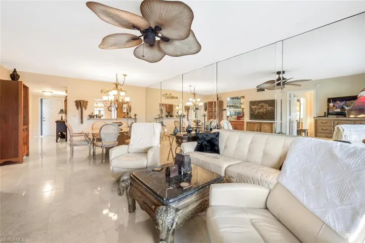Living room featuring ceiling fan with notable chandelier and light tile patterned floors