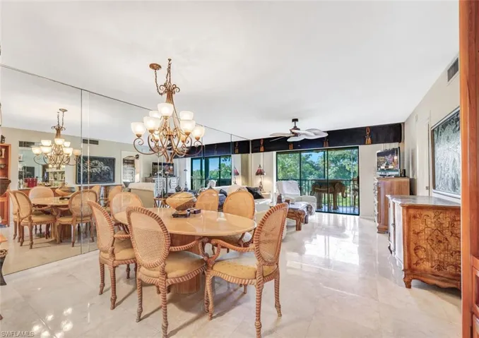 Tiled dining room with ceiling fan with notable chandelier