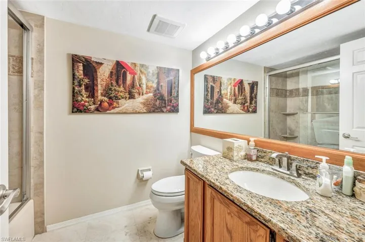 Full bathroom featuring vanity, enclosed tub / shower combo, toilet, and tile patterned floors