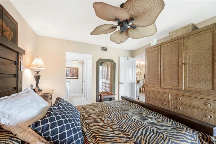 Carpeted bedroom featuring ensuite bath and ceiling fan