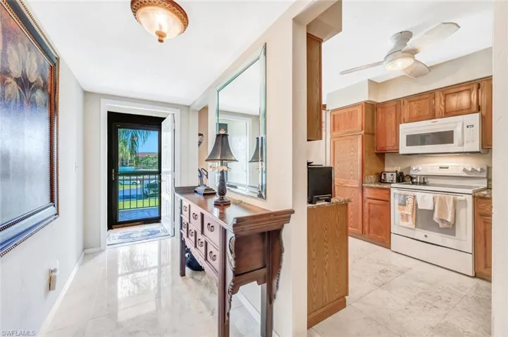 Kitchen with light tile patterned floors, ceiling fan, and white appliances