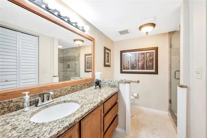 Bathroom with tile patterned floors, vanity, walk in shower, and toilet