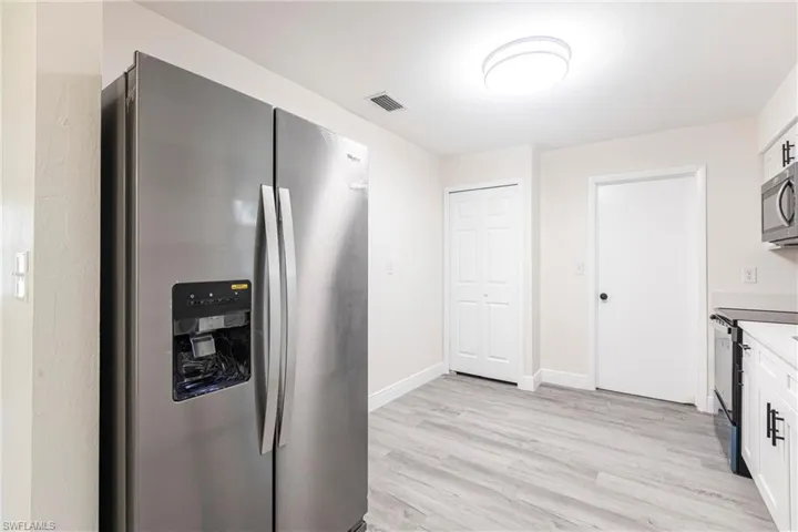 Kitchen with stainless steel appliances, light wood finished floors, and white cabinetry