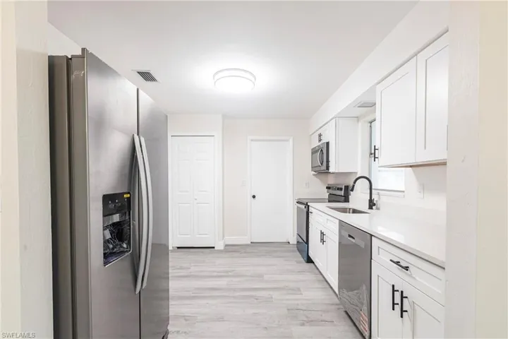 Kitchen featuring stainless steel appliances, light wood finished floors, white cabinets, and light countertops