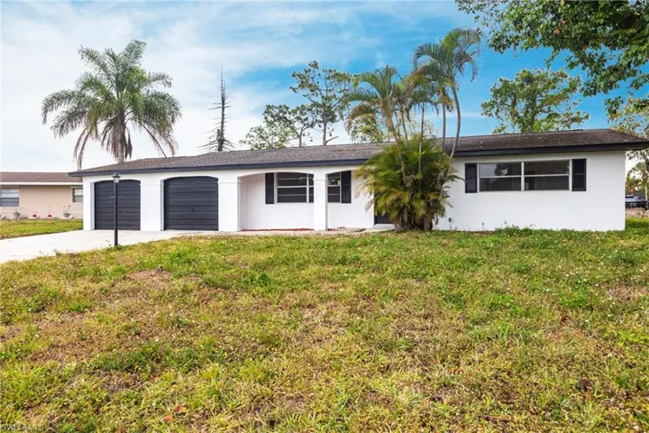 Ranch-style home featuring a garage, driveway, a front yard, and stucco siding