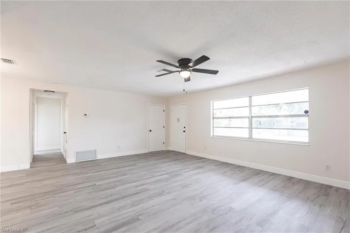 Spare room with ceiling fan, light wood-style flooring, and a textured ceiling